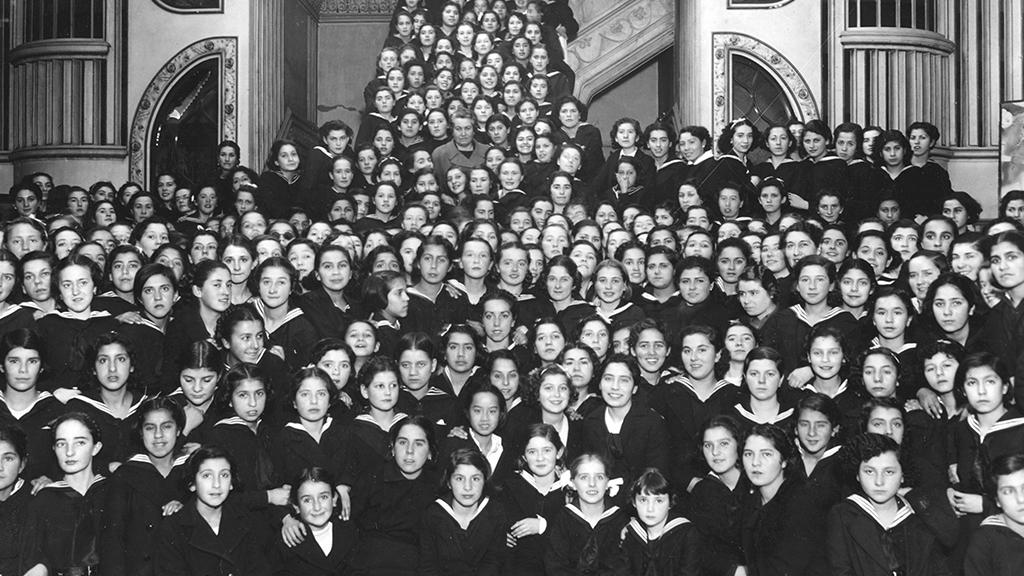 Gabriela Mistral es destacada en esta cartelera. Gabriela Mistral junto a alumnas del Liceo nº 6 de niñas de Santiago, 1921. Colección Museo Gabriela Mistral de Vicuña.