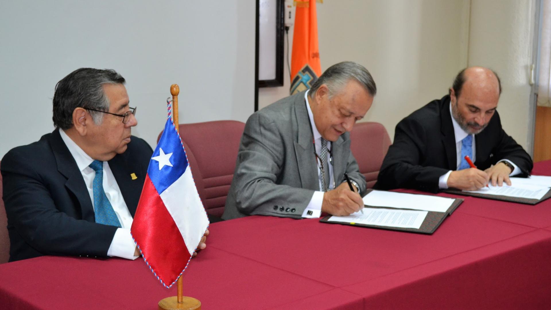 El director de la Dibam, Ángel Cabeza, firmando el convenio junto al rector de la UTA, Arturo Flores