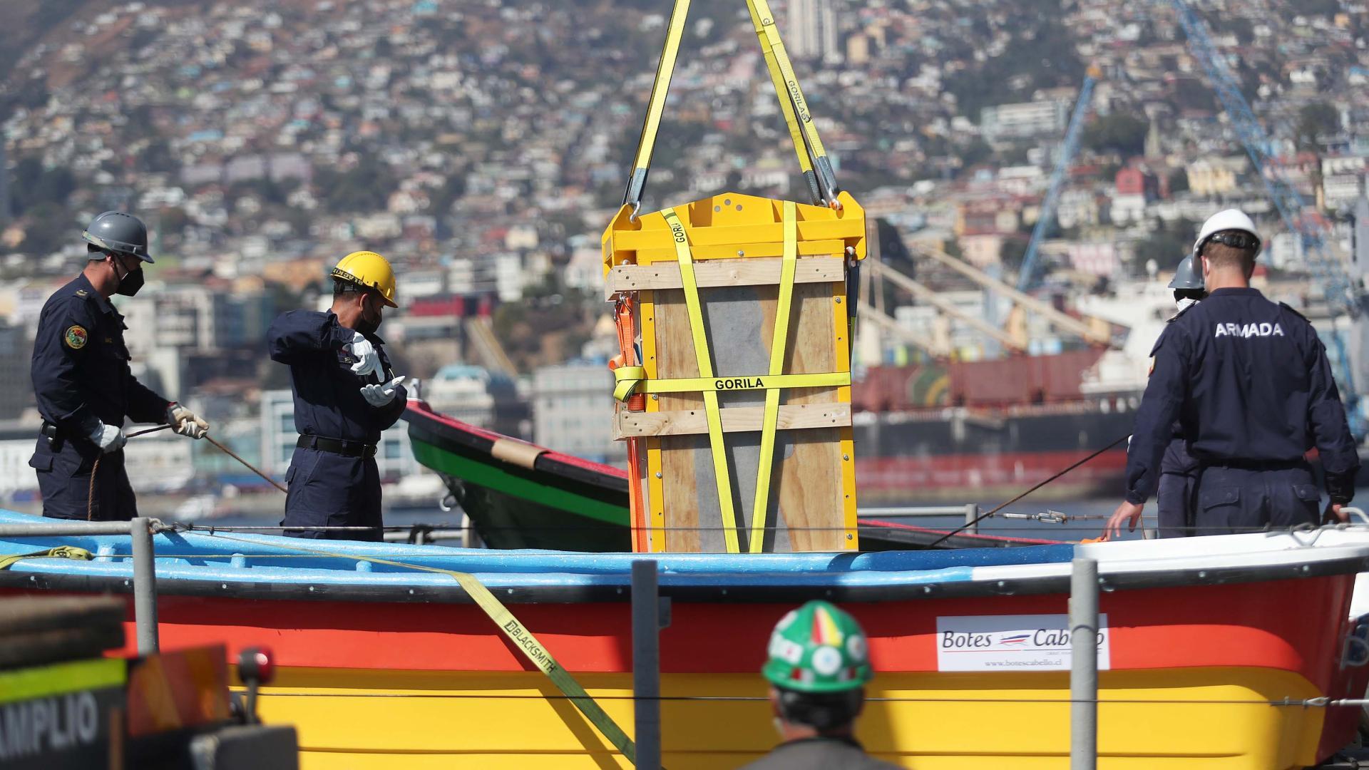 pescadores suben caja a bote en valparaíso