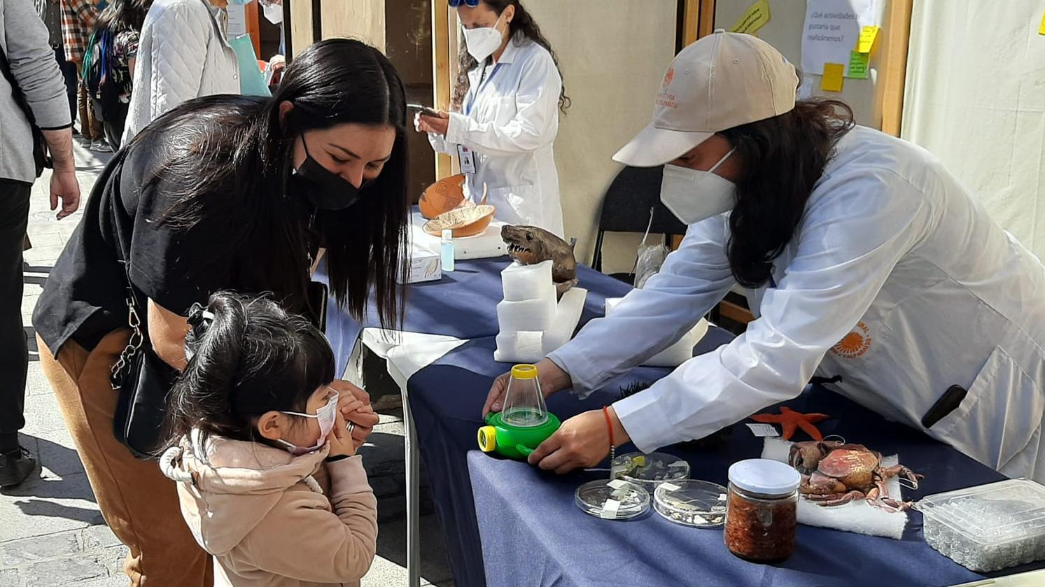 niña recibe material de funcionaria del museo