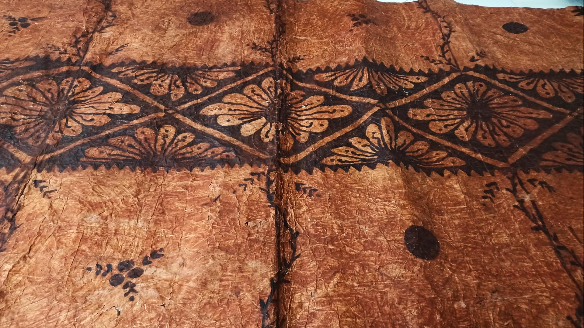 Tapa o pieza textil proveniente de Tonga, confeccionada por las fibras de mahute, con diseños de tonalidades cafés.