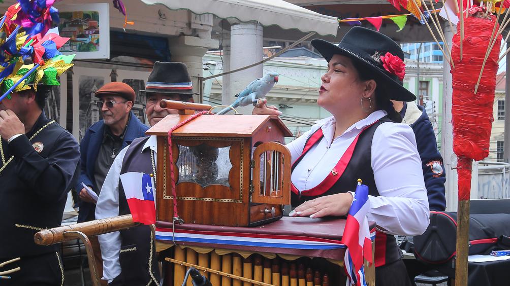Mujer organillera tocando su instrumento en la calle