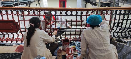 Fotografía de tres personas con batas blancas, trabajando en las rejas de los balcones 