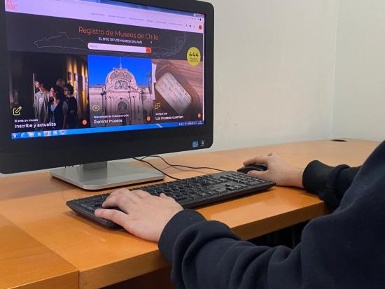 Computador de mesa con el sitio del RMC en pantalla y manos sobre el teclado.